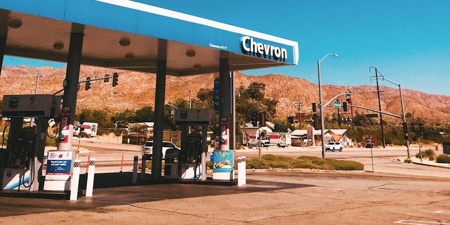 A Chevron gas station with mountains in the background under a clear blue sky in California, USA.